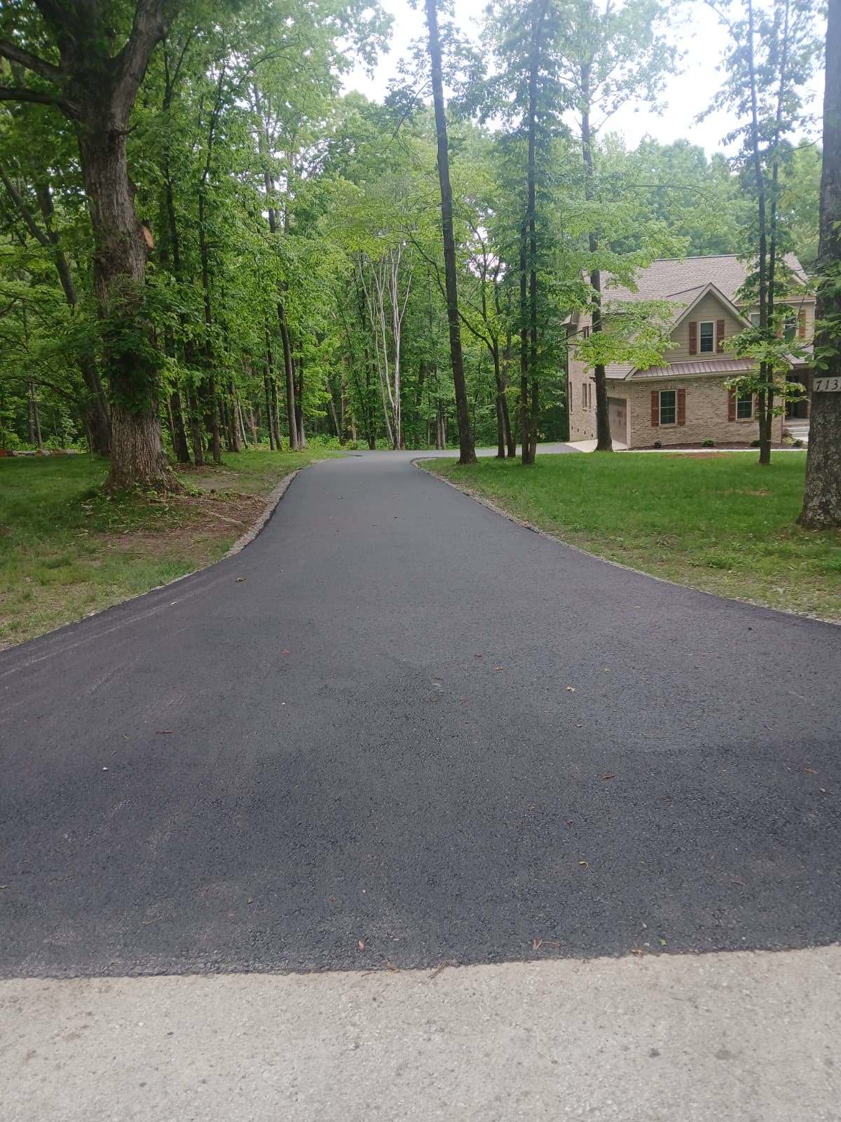 New asphalt driveway winding through a forested property