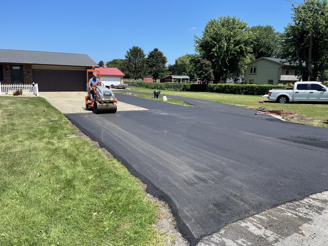 Roller compacting new asphalt driveway